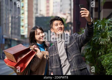 Glücklich und liebevoll junge asiatische Paar unter ein Selfie während Wandern und Einkaufen in der modernen Stadt Stockfoto