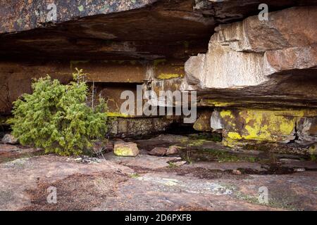 Blick auf eine Höhle inmitten erstaunlicher Felsformationen. Riesiger Block auf einem felsigen Hang. High Coast Heritage, Schweden. Stockfoto