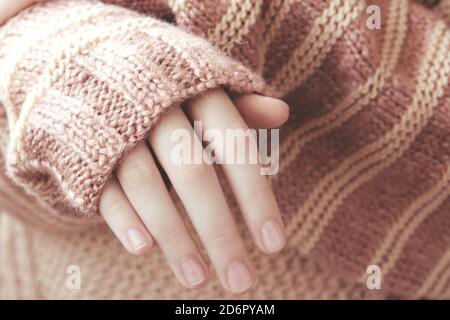 Frau in einem beigefarbenen weichen warmen Strickpullover faltete ihre Hände im Sonnenlicht. Bald Herbst Stockfoto