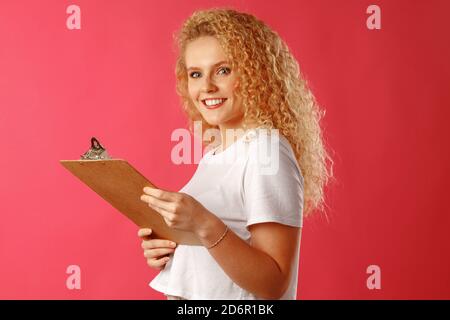 Lockige blonde Geschäftsfrau hält Zwischenablage in ihren Händen Stockfoto