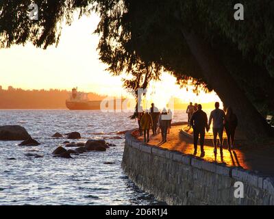 Oktober 2020, Vancouver, Kanada - Menschen wandern, laufen und joggen entlang der Ufermauer des Stanley Parks. Verankerte Schiffe im Hintergrund sichtbar. Stockfoto