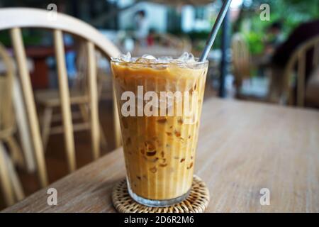 Nahaufnahme eines Glases vereisten Latte-Kaffees auf einem Holztisch Stockfoto