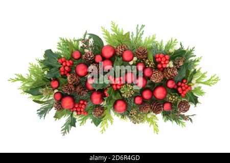 Rote Kugel Weihnachtsdekoration mit traditionellem Wintergrün von Stechpalme, Efeu, Mistel, Tannenzapfen und Zedernzypresseblättern. Stockfoto