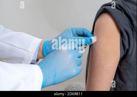 Der Arzt injiziert männliche Patienten. In der Hand des Arzters haben Spritzen. Stockfoto