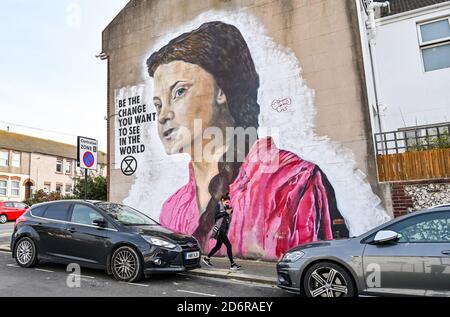 Brighton UK 19. Oktober 2020 - EINE junge Frau geht an einem hellen Herbsttag an einem riesigen Greta Thunberg-Wandgemälde an einer Wand im Queens Park in Brighton vorbei. Das Wetter wird in den nächsten Tagen immer wechselhafter werden, mit Wind und Regen für die meisten Teile des Landes vorhergesagt : Credit Simon Dack / Alamy Live News Stockfoto