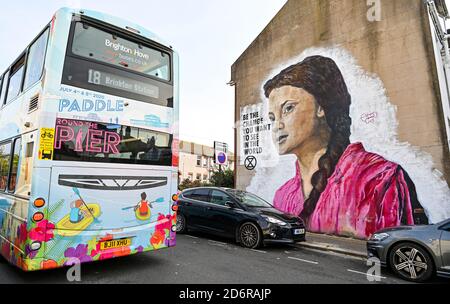 Brighton UK 19. Oktober 2020 - EIN lokaler Bus fährt an einem hellen Herbsttag an einem riesigen Greta Thunberg-Wandgemälde an einer Wand im Queens Park in Brighton vorbei. Das Wetter wird in den nächsten Tagen immer wechselhafter werden, mit Wind und Regen für die meisten Teile des Landes vorhergesagt : Credit Simon Dack / Alamy Live News Stockfoto