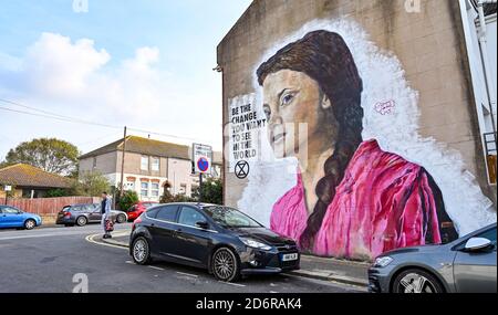 Brighton UK 19. Oktober 2020 - EIN junger Mann geht an einem hellen Herbsttag an einem riesigen Greta Thunberg-Wandgemälde an einer Wand im Queens Park von Brighton vorbei. Das Wetter wird in den nächsten Tagen immer wechselhafter werden, mit Wind und Regen für die meisten Teile des Landes vorhergesagt : Credit Simon Dack / Alamy Live News Stockfoto