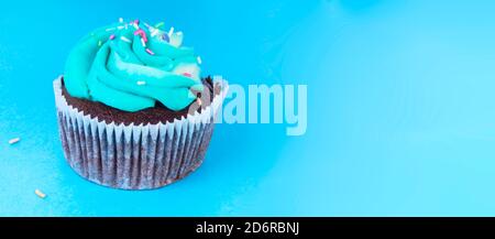 Frische hausgemachte Schokolade Cupcake mit bunten Dekoration dekoriert, leckere und lustige Muffin mit bunten Süßigkeiten auf blauem Hintergrund, Urlaub oder p Stockfoto