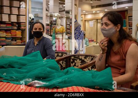 Dehradun, Uttarakhand/Indien-Oktober 14 2020:zwei schöne Damen, die in einem Geschäft für einen Saree einkaufen, tragen Gesichtsmaske in Corona Epidemie in Indien. . Hochwertige Fotos Stockfoto