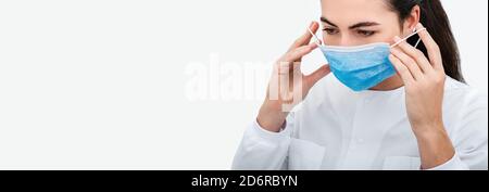 Nahaufnahme des Gesichts einer Ärztin, während sie in einem Krankenhaus eine Schutzmaske aufsetzt. Schutzmittel während einer globalen Pandemie Stockfoto
