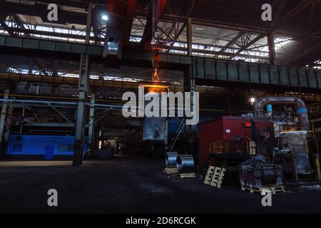 Eisenguss und die Gießerei. Deckenkran mit Schöpfkelle aus geschmolzenem Metall in der metallurgischen Fabrik Stockfoto