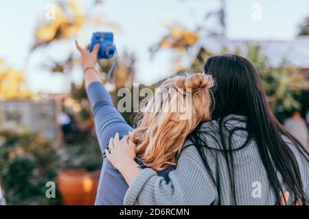 Zwei femaile Freunde machen Selfie-Foto mit Instant-Kamera, Rückansicht Stockfoto