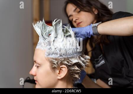 Haarfärbeprozess mit Folie. Schöne Frau Friseur in den Prozess der Färbung von Haaren an den Kunden mit Folie Stockfoto