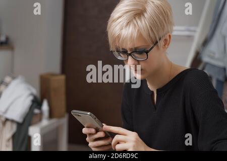 Porträt einer schönen jungen blonden Frau mit ihrer Zelle Telefon zu Hause Stockfoto