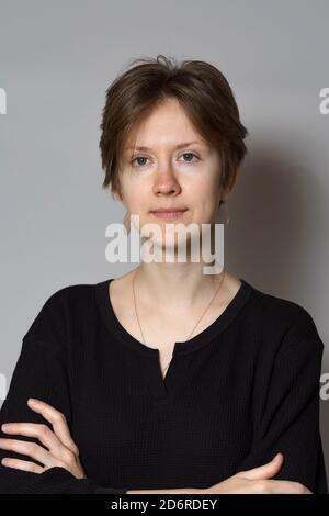 Porträt einer 30-jährigen braunhaarigen Frau auf grauem Hintergrund Stockfoto