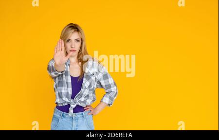 Porträt einer ernsthaften jungen Frau zeigt Stop-Geste mit Ihre Handfläche war auf gelbem Hintergrund isoliert Stockfoto
