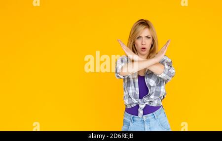 Porträt einer ernsthaften jungen Frau zeigt Stop-Geste mit Ihre Handfläche war auf gelbem Hintergrund isoliert Stockfoto