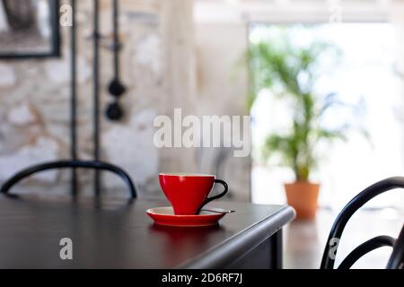 Rote Kaffeetasse auf schwarzem Tisch in einem Café Stockfoto