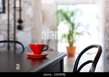 Rote Kaffeetasse auf schwarzem Tisch in einem Café Stockfoto