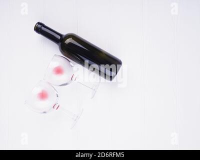 Zwei Gläser mit Weinresten und eine Flasche liegen auf weißem Hintergrund, Platz für Text. Stockfoto
