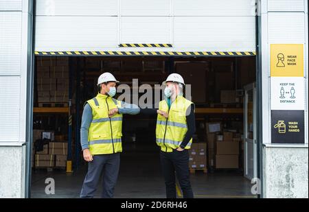 Arbeiter mit Gesichtsmaske Begrüßung vor dem Lager, Coronavirus Konzept. Stockfoto