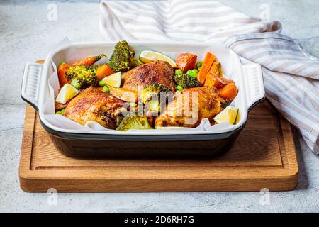 Gebackenes Huhn mit Gemüse, grauer Hintergrund. Stockfoto