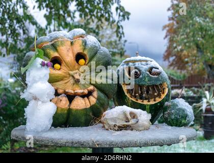 Erster Schnee, geschnitzte dekorative Kürbisse im Garten, erster Schnee auf Kürbisdekoren, halloween, Kürbisdekor, Herbstzeit Stockfoto