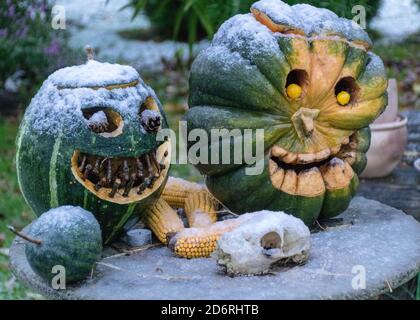 Erster Schnee, geschnitzte dekorative Kürbisse im Garten, erster Schnee auf Kürbisdekoren, halloween, Kürbisdekor, Herbstzeit Stockfoto