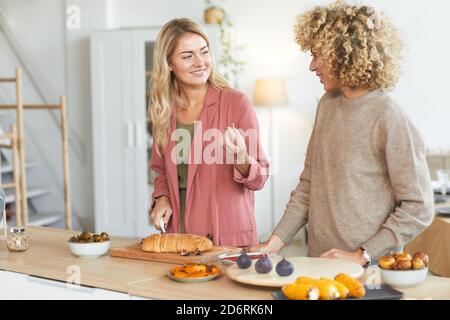 Taille up Porträt von zwei jungen Frauen glücklich chatten während Kochen für Dinner-Party drinnen, kopieren Raum Stockfoto