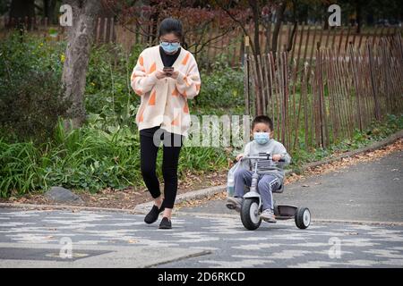 Eine Mutter und ihr Sohn auf einem Dreirad in einem Park in Queens, New York City.autumn, Herbst, Stockfoto