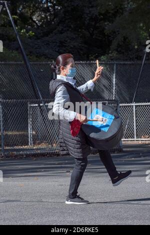 Ein asiatisch-amerikanisches Mitglied eines Trommelensembles probt in einem Park in Queens, New York City, während es eine chirurgische Maske trägt. Stockfoto