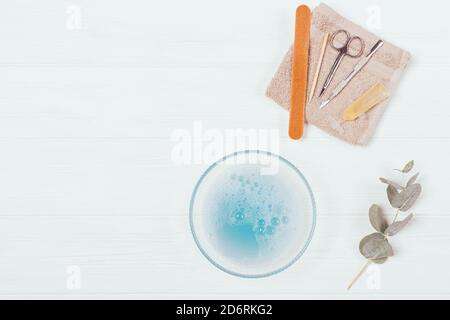 Flat Lay Zusammensetzung Werkzeuge für Home Maniküre in der Nähe Schüssel mit Seifenwasser und Eukalyptus Zweige auf weißem Hintergrund. Stockfoto