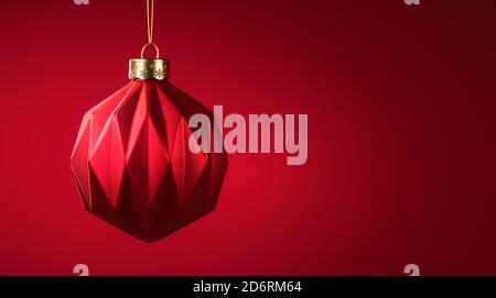 Rot matt Weihnachtskugel hängt an goldenen Schnur. Weihnachtsschmuck mit modernem geometrischen Muster. Weihnachtsdekoration, festliches Atmosphärenkonzept. Stockfoto