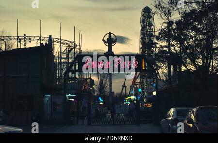 LED beleuchtete Schild eines luna Park mit Riesenrad und andere Kirmes Spielzeug auf Hintergrund mit schönen Nachthimmel, breiterer Winkel Stockfoto