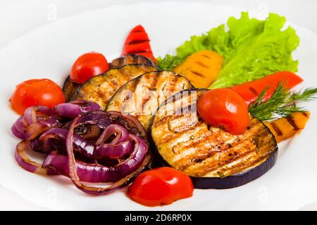 Gemüsesalat mit gegrillter Aubergine, Kirschtomaten, roten und gelben Paprika, lila Zwiebeln, Dill, Salatblatt. Gegrilltes gesundes Gemüse ist Stockfoto