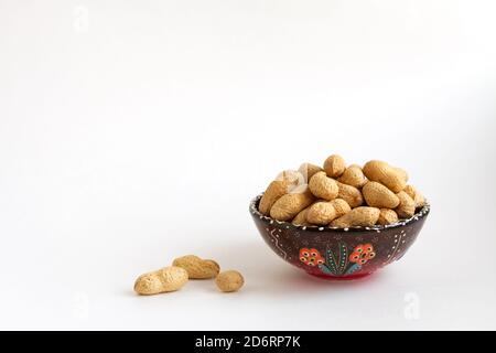 Nüsse in Schale auf Tonbecher auf weißem Hintergrund, kopieren Raum für Text Stockfoto