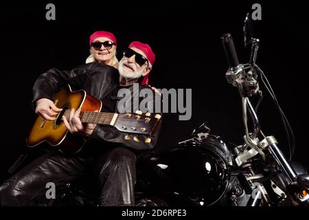 Foto von alten Biker Mann Dame paar sitzen Chopper Moto Rock Bike Festival Treffen spielen singen Gitarre erinnern Jugend Zeiten Tragen Sie modisches Rockerleder Stockfoto