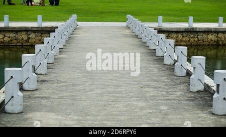 Betonfußgängerschutz in der Nähe eines Sees in einem Park. Weiße kleine Betonpfosten auf einem Gehweg. Stockfoto