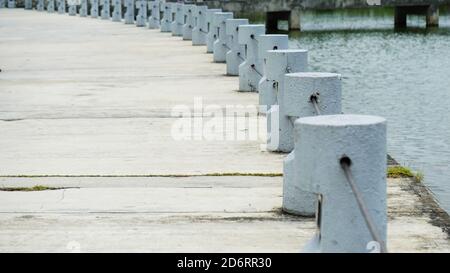 Betonfußgängerschutz in der Nähe eines Sees in einem Park. Weiße kleine Betonpfosten auf einem Gehweg. Stockfoto