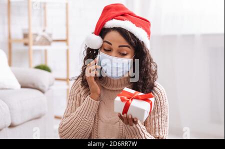 Schwarze Frau In Maske Im Gespräch Am Telefon Halten Geschenkbox Stockfoto