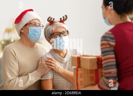 Menschen mit Geschenken tragen Gesichtsmasken während Coronavirus und Grippe Ausbruch an Weihnachten. Schutz vor Viren und Krankheiten, Quarantäne zu Hause. COVID-2019 Stockfoto