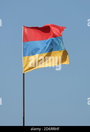 Armenische Flagge auf Fahnenmast auf blauem Himmel Hintergrund fliegen Stockfoto