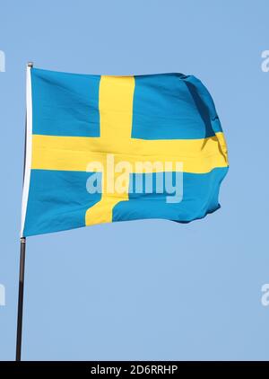 Schwedische Flagge auf Fahnenmast auf blauem Himmel Hintergrund fliegen Stockfoto