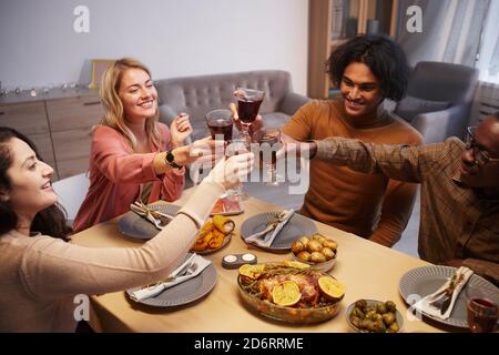 High-Angle-Ansicht auf multi ethnische Gruppe von glücklichen Menschen Toasting während genießen Abendessen Party mit Freunden und Familie Stockfoto