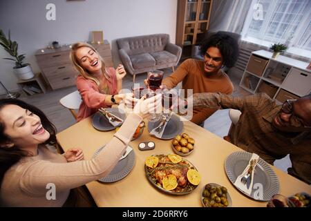 High-Winkel-Ansicht bei der multiethnischen Gruppe der fröhlichen jungen Leute toasten, während sie Dinner-Party mit Freunden und Familie genießen Stockfoto