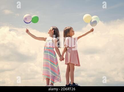 Glückliche Kindheit. Sommerurlaub. Kleine Mädchen umarmen. Liebe und Unterstützung. Konzept der Schwesternschaft und Freundschaft. Familie Bindung Zeit. Beste Freunde mit Ballon. Zwei Schwestern halten Party Ballon. Stockfoto