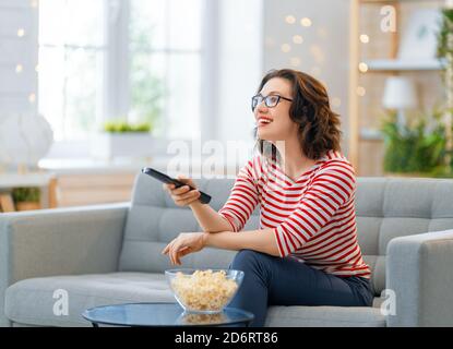 Junge Frau beim Fernsehen, Filme mit Popcorn. Mädchen verbringt Zeit zu Hause. Stockfoto