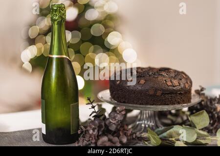 Appetitlich Schokolade Kuchen und eine Flasche kalten erfrischenden Champagner platziert Auf dem Tisch im Zimmer für Weihnachtsfeier Stockfoto