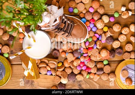 Holländischer Urlaub Sinterklaas. Holzhintergrund mit Kinderschuh mit Karotten für Santa's Pferd, Pepernoten und Süßigkeiten. Blick von oben. Hochwertige Fotos Stockfoto