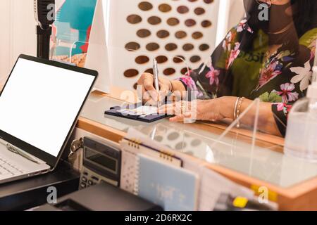 Ältere Frau in Schutzmaske Unterschrift Kreditkarte im Bekleidungsgeschäft. Stockfoto